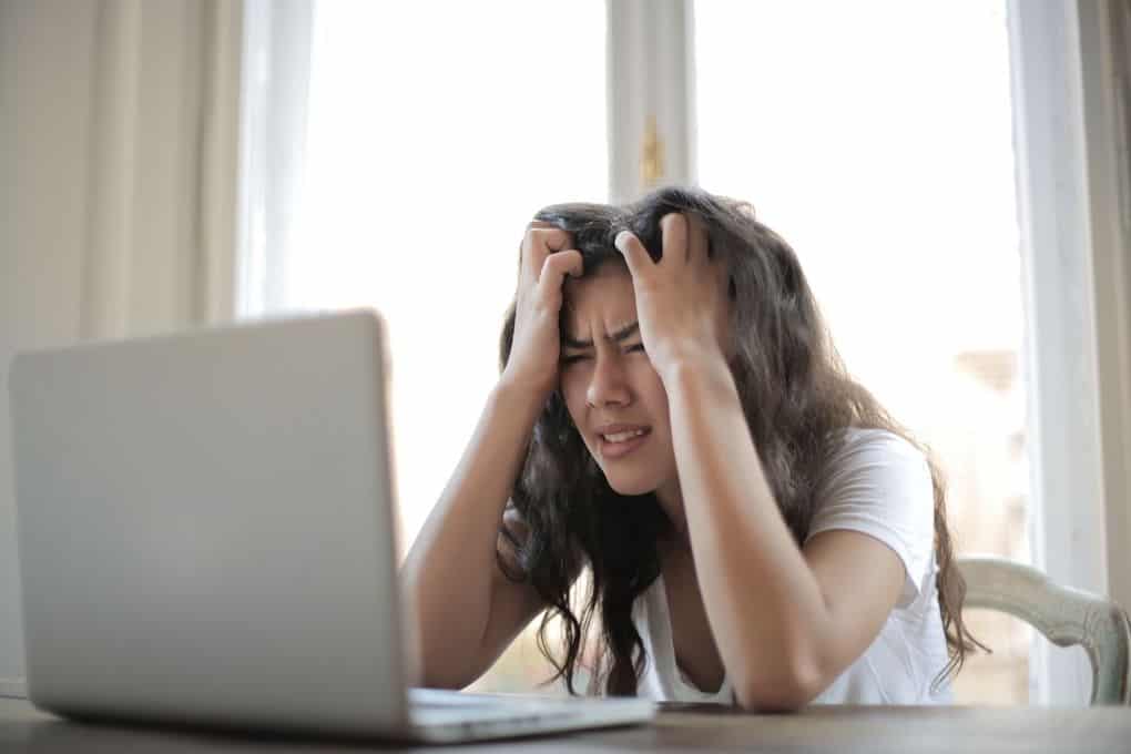 A person appears frustrated in front of their computer screen. P2P platforms can cause unexpected frustration for business owners and customers.
